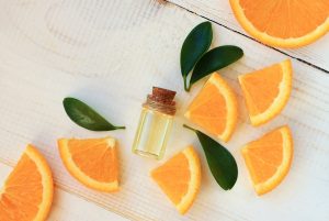 Orange aroma oil. Bottle with essential oil, citrus scattered on wooden table.