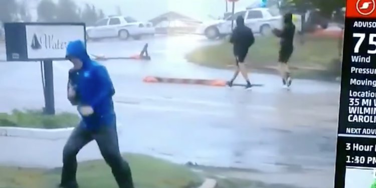 Weather Channel reporter filmed being overly-dramatic as men in shorts casually stroll by